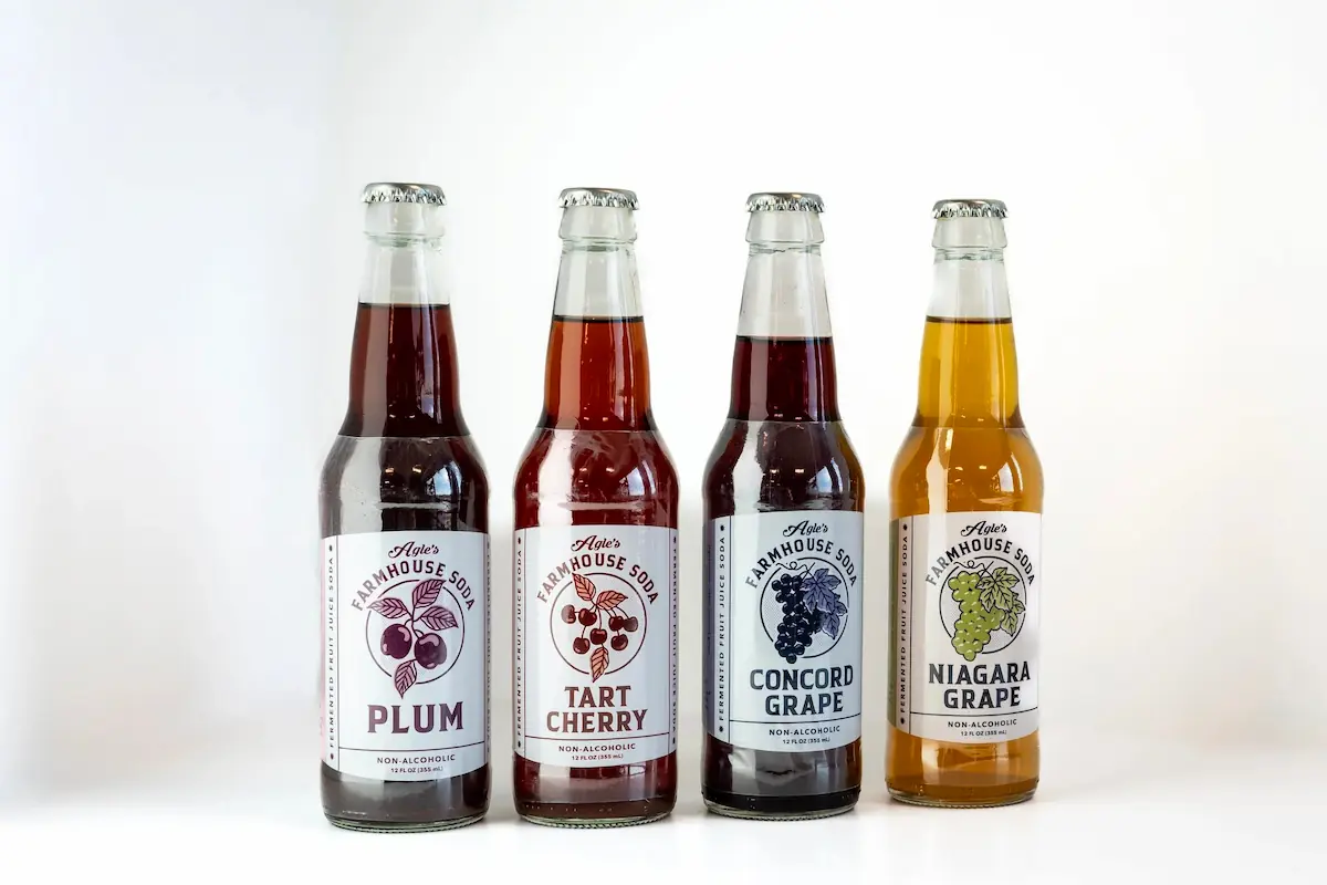 All four Agle's Farmhouse Soda flavors lined up: Plum, Tart Cherry, Concord Grape, Niagara Grape